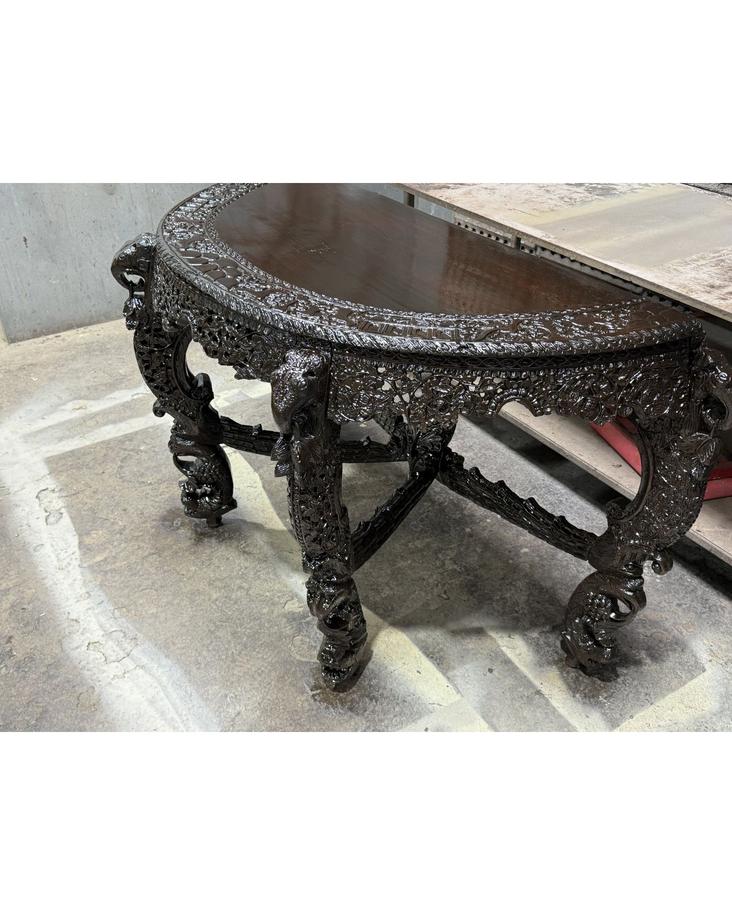 Ornately carved dark wooden table with detailed relief carvings