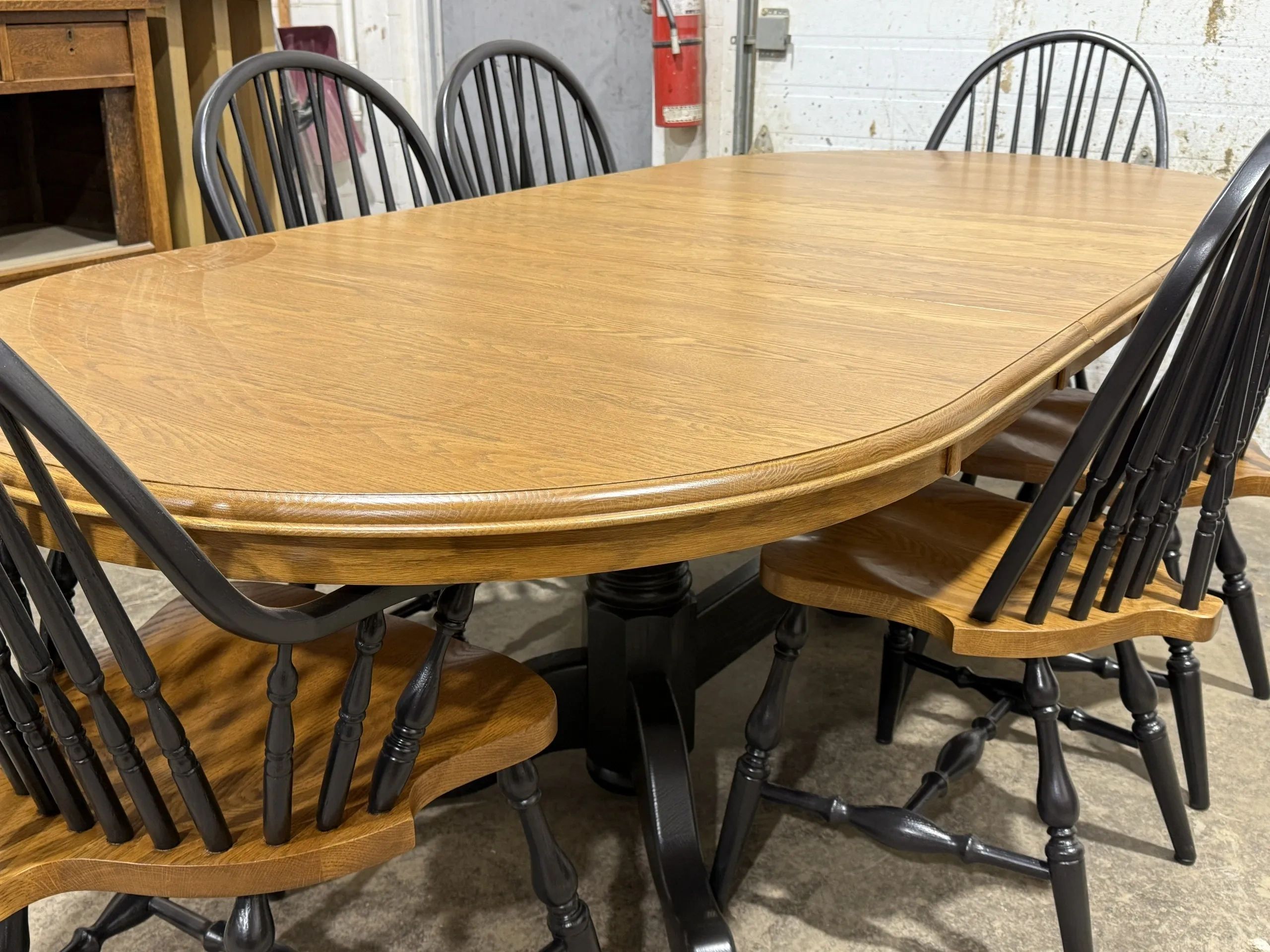 Wooden dining table with natural oak finish and black Windsor chairs