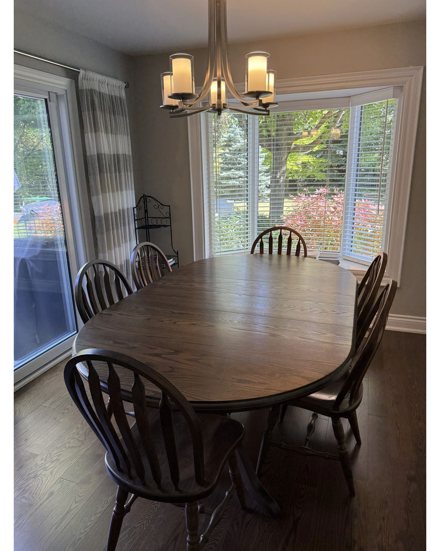 Bright dining room with restored wooden oval table and black Windsor chairs